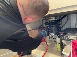 Man inspecting under the sink - ClogPro in Portland OR and Vancouver WA